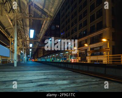 low angle view of a wooden platform next to a train track downtown at night Stock Photo