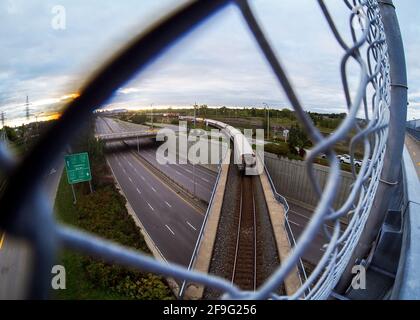 train coming back from the city on a bridge on top of a highway Stock Photo