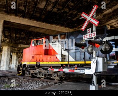 big red and black locomotive under a concrete bridge Stock Photo