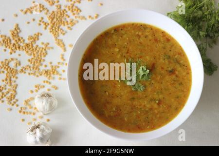 Boiled lentils tempered with garlic and spices. A favourite side dish from India popularly known as Yellow Daal Tadka. Shot on white background Stock Photo