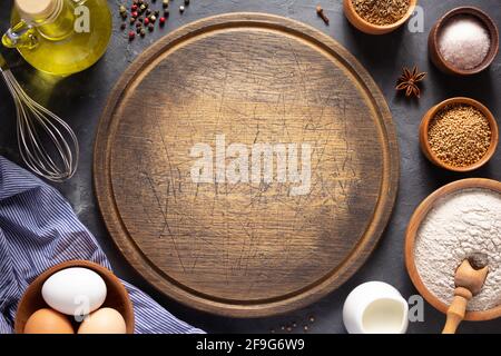 Pizza or bread cutting board with bakery ingredients for homemade baking on table. Food recipe concept at stone background texture with copy space. Fl Stock Photo