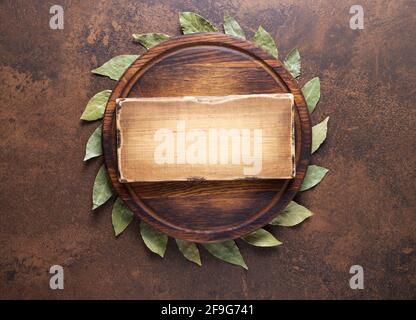 Pizza or bread cutting board and laurel leaf for homemade baking on table. Food recipe concept at stone or marble background texture with copy space. Stock Photo