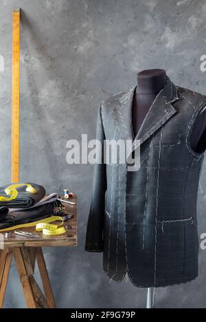 suit jacket on male tailor mannequin and sewing tools, creative concept of clothes atelier Stock Photo
