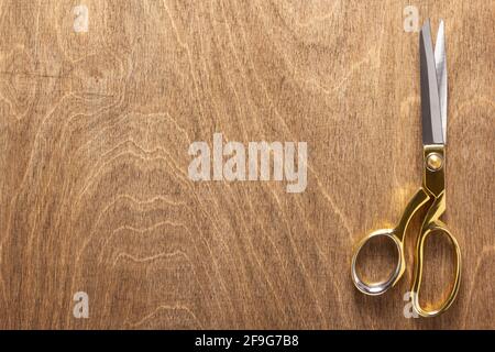 tailor or sewing scissors on wooden table background, flat lay top view Stock Photo