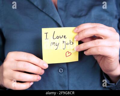 I Love My Job Note in hand, business woman or man with yellow sticky note with positive achievement, business,goals,education,people concept Stock Photo