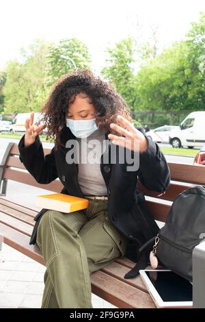 Young girl frustrated with a book while sitting on an outdoor bench. Stock Photo