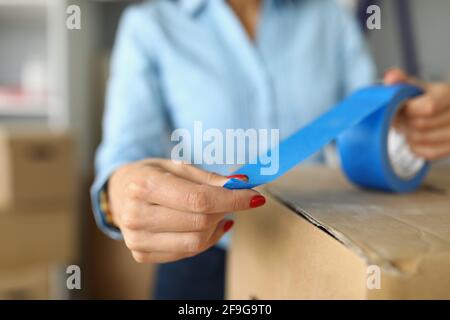 Close-up of female packs up things in carton boxes with blue scotch Stock Photo