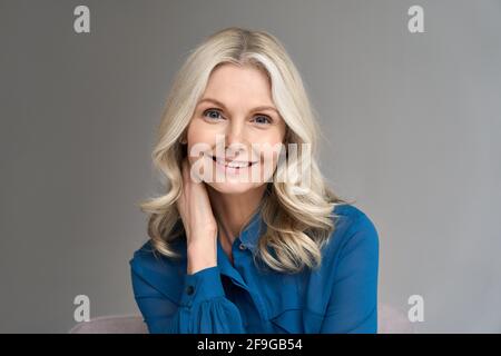Portait of happy mature 50 years old business woman isolated on grey background. Stock Photo