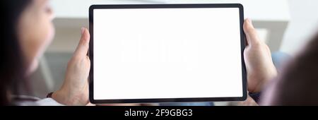 Woman and man are sitting on couch at home and holding tablet in their hands closeup Stock Photo
