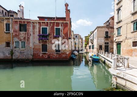 Venice, Italy - June, 21, 2013: Typical view of gondolas and boats covered with a special cloth on the canal of Venice. Old buildings around. Perfect Stock Photo