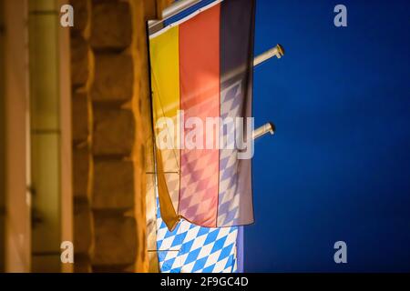 Berlin, Germany. 18th Apr, 2021. The Bavarian flag shines through behind the German flag at the State Representation of Bavaria in the evening. Credit: Christoph Soeder/dpa/Alamy Live News Stock Photo