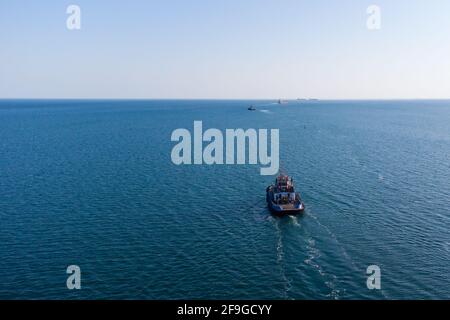 The sea tug moves from the port water area towards the open sea. Photo from the helicopter. View from above Stock Photo