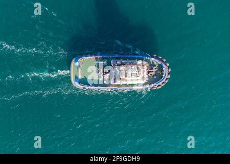 The sea tug moves from the port water area towards the open sea. Photo from the helicopter. View from above Stock Photo