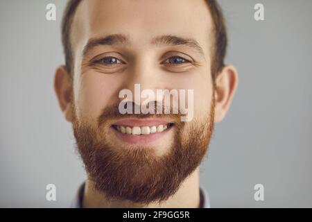 Closeup studio portrait of a happy friendly bearded young man smiling at the camera Stock Photo
