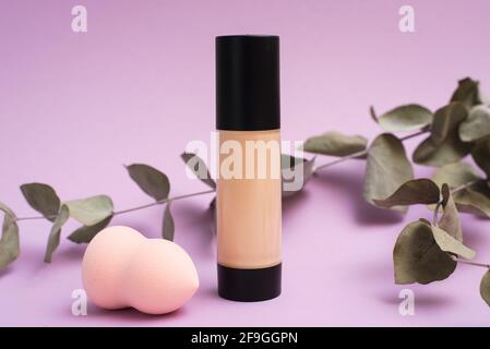 A face foundation cream and sponge next to a eucalyptus branch. The concept of natural makeup, the use of natural ingredients. Stock Photo