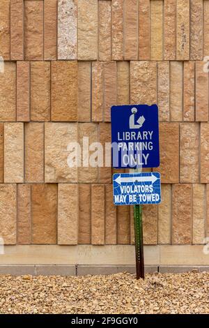 Close up view of a library parking sign in front of an attractive modern limestone wall with unique rough textured vertical shaped natural stone brick Stock Photo