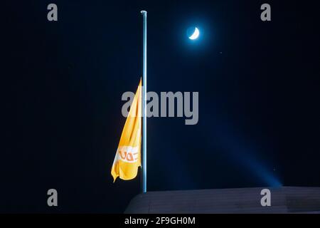 Berlin, Germany. 18th Apr, 2021. The moon shines in the evening behind the CDU flag of the Konrad Adenauer House, which is flying at half-mast and only faintly. Credit: Christoph Soeder/dpa/Alamy Live News Stock Photo