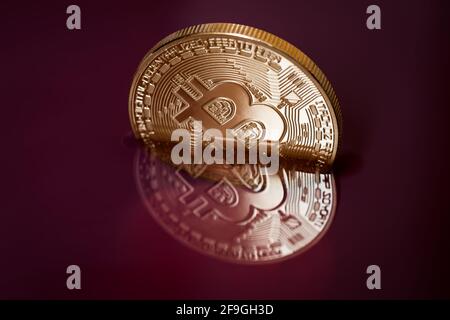 Cryptocurrency coin in red liquid. Bitcoin underwater. The sinking of a golden coin. Stock Photo