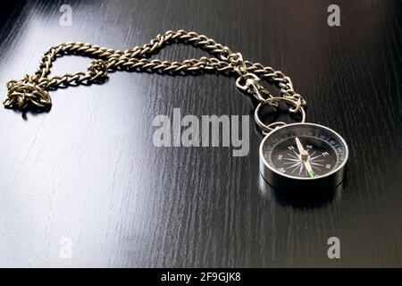 Compass on a chain on a wooden table close up Stock Photo