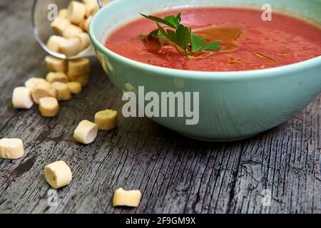 Close-up view of Gazpacho bowl with parsley and extra virgin olive oil, accompanied by croutons around. Concept of mediterranean food, vegan, healthy. Stock Photo