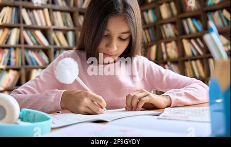Pretty latin indian schoolgirl doing homework, learning at home. Stock Photo