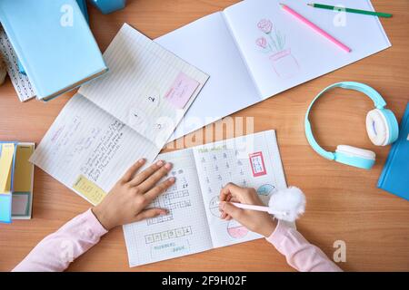 Table top view of child hands writing doing homework on math at home. Stock Photo