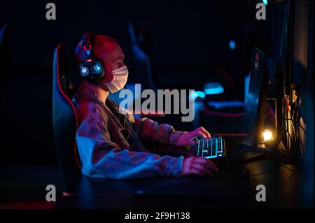 An online strategy tournament for esports players in the cyber games arena. A professional masked gamer. Stock Photo