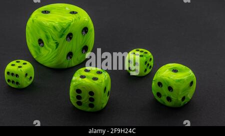 green dice with different size on a black background Stock Photo