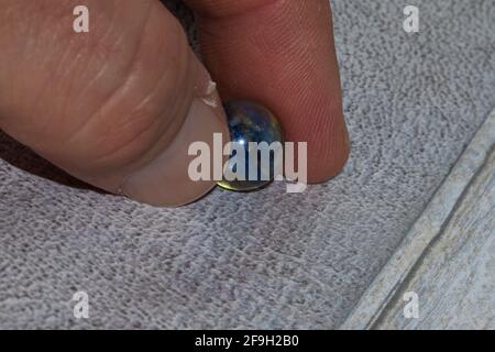 fingers holding glass marble on clear background Stock Photo
