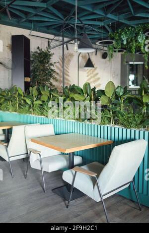 Vertical background image of eco friendly cafe interior with focus on cozy seating area with armchairs and table decorated by fresh green plants, copy Stock Photo