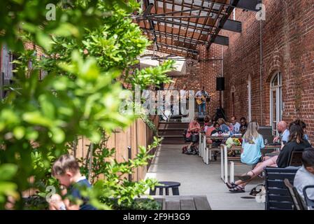 Outdoor dining with live music in the outdoor alcove between Banks Food Hall and Whitewater Express along the RiverWalk in Uptown Columbus, Georgia. Stock Photo