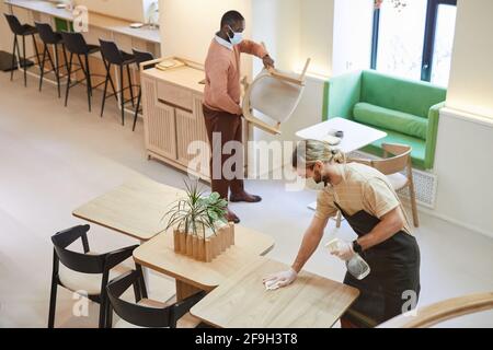 High angle view at two people cleaning tables in cafe while preparing for opening in morning, copy space Stock Photo