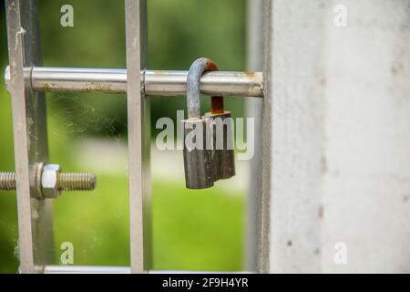 A closeup of a padlock on a metal fence in a field with a blurry background Stock Photo