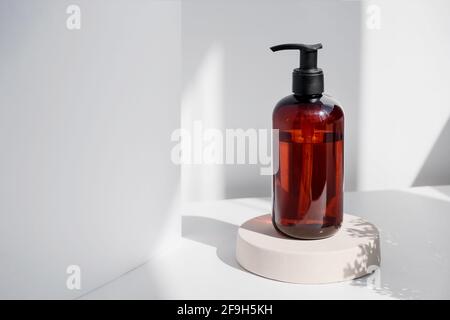 Brown glass bottle on white background in the morning rays of light. Eco cosmetic cream, serum for skin, face and body. Concept of skincare, spa and Stock Photo