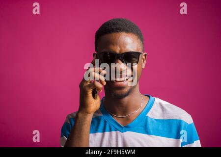 Portrait of an excited African man talking on a phone against a pink background Stock Photo