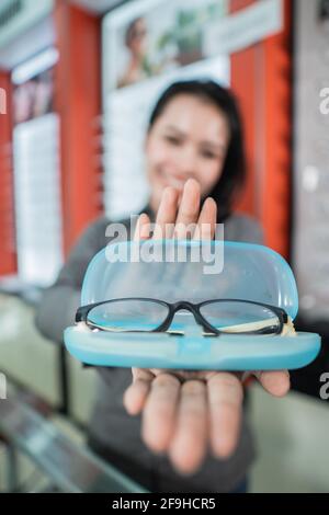 selective focus of the glasses in the eyeglass box with the background of a beautiful smiling woman Stock Photo