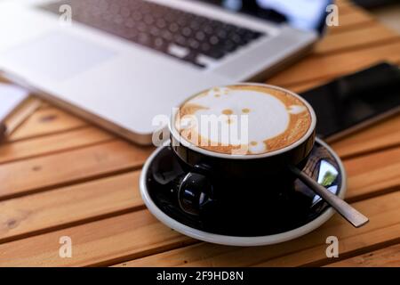 Top view hot coffee cup with blur laptop smarthphone and note book on wood table. office desk with smart phone laptop and coffee cup. Business concept Stock Photo