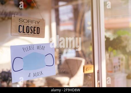 Sorry we are closed wood sign and  Please wear face mask befor enter paper on glass door Protection to pandemic of coronavirus. Close store,restaurant Stock Photo