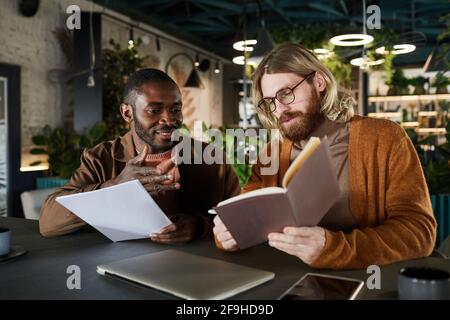 Portrait of two contemporary men collaborating on project during business meeting in green office or cafe interior, copy space Stock Photo