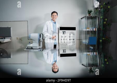 a male doctor posing next to an eye test kit Stock Photo