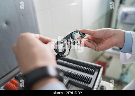 a doctor's hand is holding the experimental lens frame in a room Stock Photo