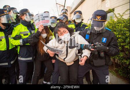 Students' protest against Japan to release water from Fukushima, Apr 17, 2021 : Policemen block college students trying to hold a press conference in front of the Japanese embassy in Seoul, South Korea, while their colleague protesters stage a sit-down demonstration in front of the embassy. They were protesting against the Japanese government's decision to discharge radioactive water from Fukushima. Signs read,'Japan cancel the decision to discharge radioactive water!' (front) and 'We strongly condemn U.S. administration that has expressed its support for the Japanese government's decision to Stock Photo