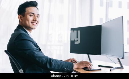 Asian business people are focused on working. A computer with two blank screens Stock Photo
