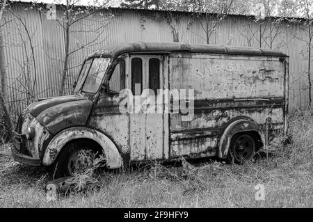 B&W photo of abandoned, rusted Virginia Dairies truck in front of metal building Stock Photo