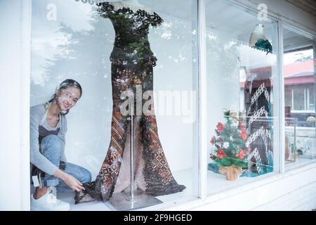 portraits of young women in glass windows cleaning and selling traditional batik clothes Stock Photo