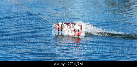 Mackay, Queensland, Australia - April 2021: Man learning to wakeboard at a cable ski park and falling off as the rope p Stock Photo