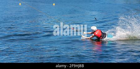 Mackay, Queensland, Australia - April 2021: Man learning to wakeboard at a cable ski park and falling off as the rope p Stock Photo