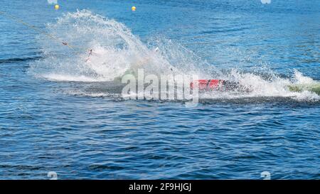 Mackay, Queensland, Australia - April 2021: Man learning to wakeboard at a cable ski park and falling off as the rope p Stock Photo
