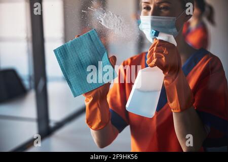 Woman in a disposable face mask cleaning the office Stock Photo