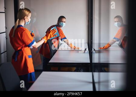 Two workers in rubber gloves cleaning surfaces with absorbent cloths Stock Photo